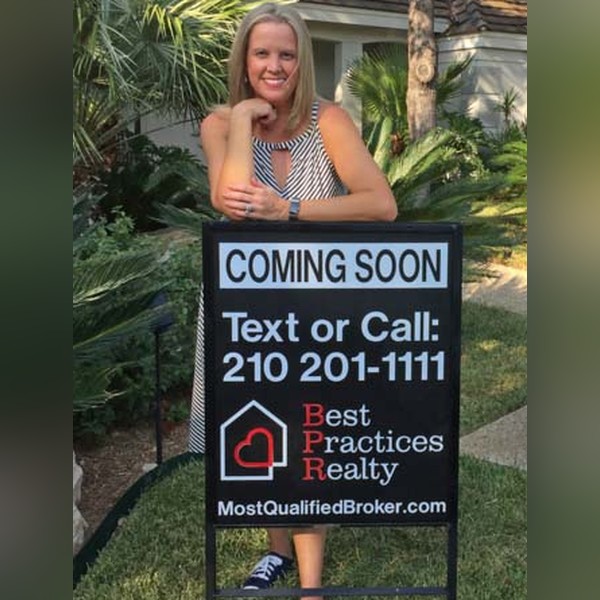 Leah McNamara standing behind a coming soon yard sign